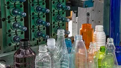 The plastic bottles and injection mold in background. PET plastic bottle manufacturing concept.