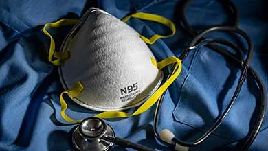 N95 mask and stethoscope on blue medical scrubs.