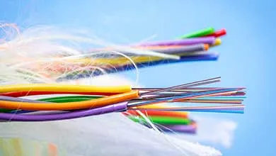 Stripped fiber optic cables revealing multicolored glass filaments against a vibrant blue background.
