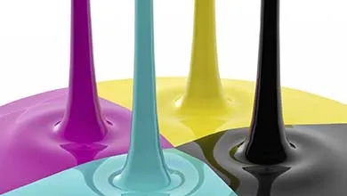 Streams of glossy liquid colorants in purple, teal, yellow, and black flowing vertically onto a smooth surface.