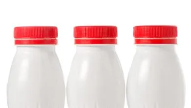 three white bottles with red caps on a white background